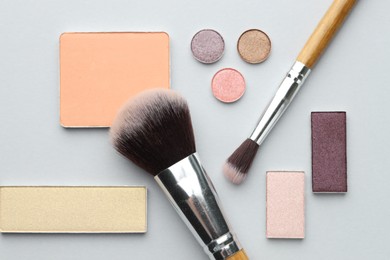 Photo of Beautiful eyeshadow refill pans and brushes on light background, flat lay