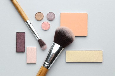 Photo of Beautiful eyeshadow refill pans and brushes on light background, flat lay