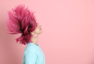Photo of Beautiful woman with bright dyed hair shaking head on pink background, space for text
