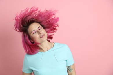 Photo of Beautiful woman with bright dyed hair shaking head on pink background, space for text