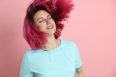 Photo of Beautiful woman with bright dyed hair shaking head on pink background