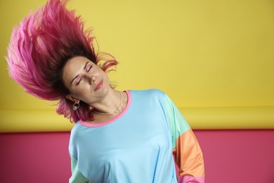 Photo of Beautiful woman with pink dyed hair shaking head on color background