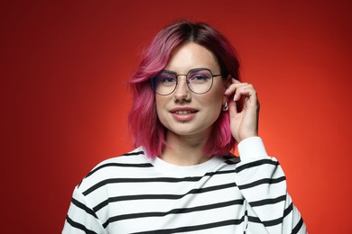 Photo of Beautiful woman with pink dyed hair in glasses on red gradient background