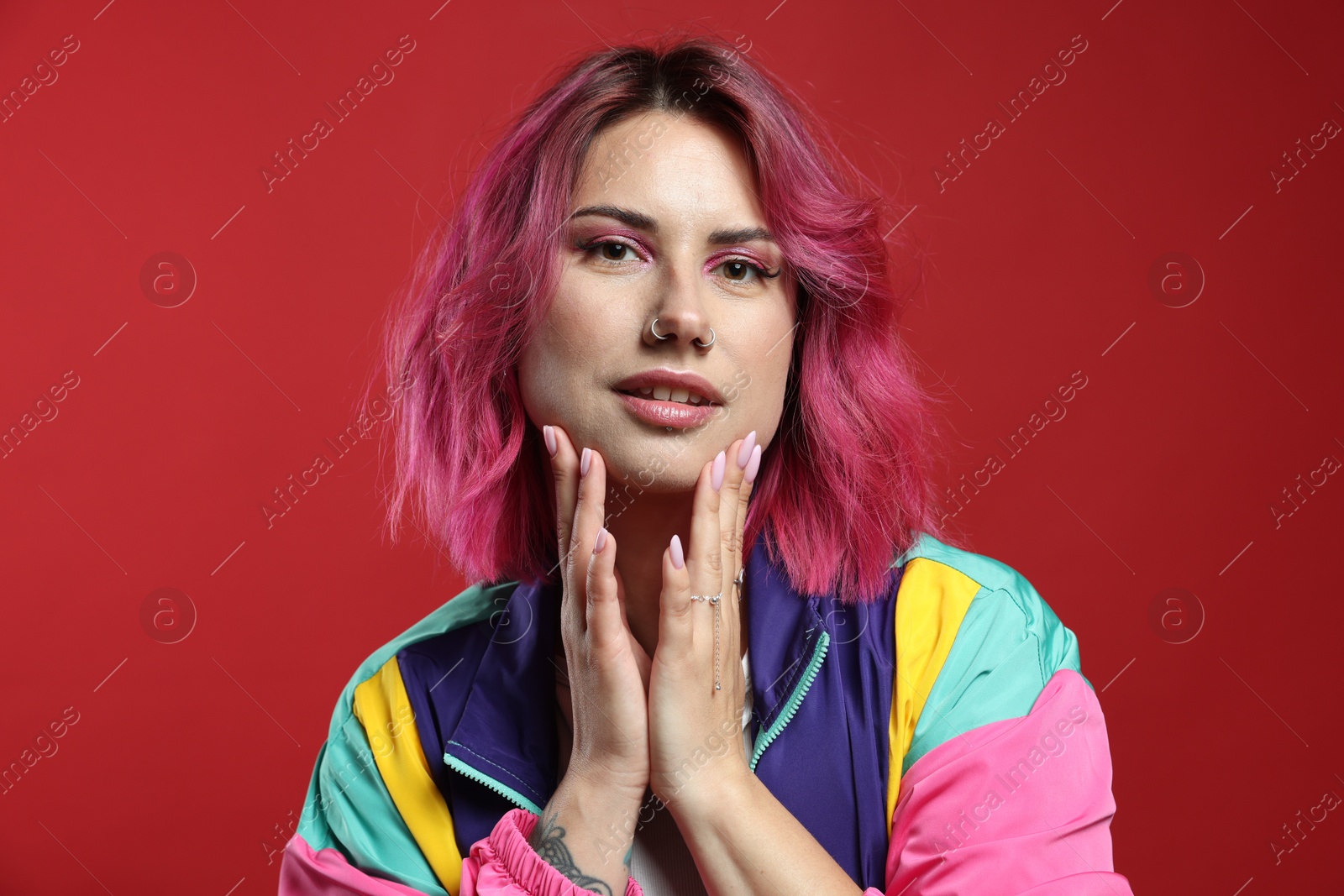 Beautiful woman with pink dyed hair on red background Photo of Beautiful woman with pink dyed hair on red background