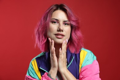 Photo of Beautiful woman with pink dyed hair on red background