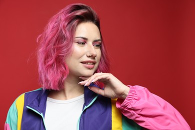 Photo of Beautiful woman with pink dyed hair on red background
