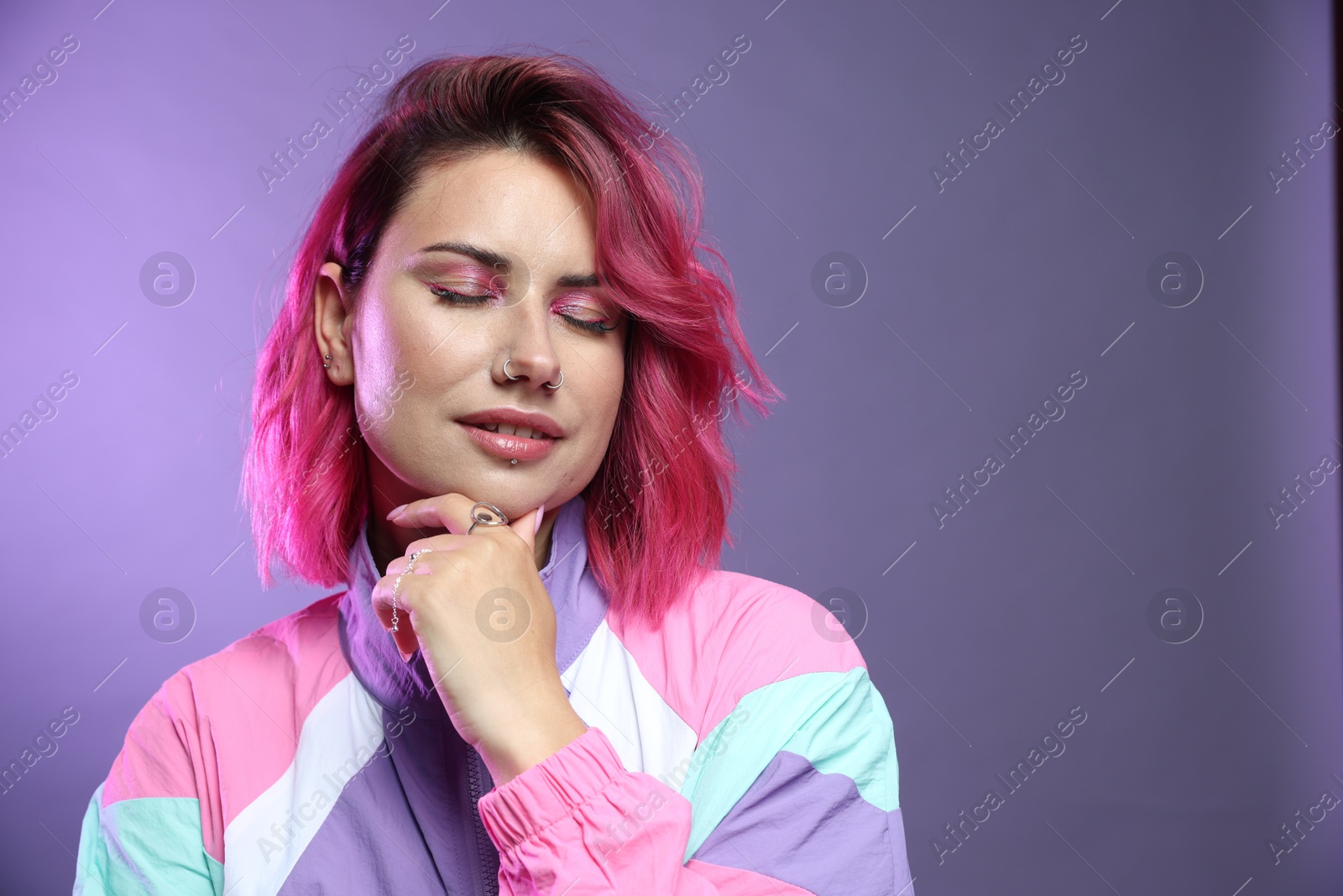 Beautiful woman with pink dyed hair on violet background, space for text Photo of Beautiful woman with pink dyed hair on violet background, space for text