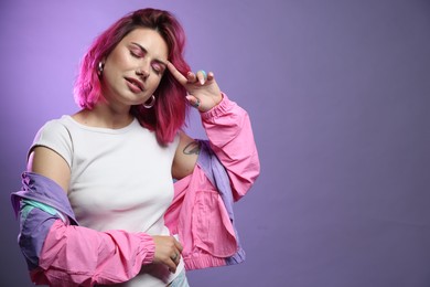 Photo of Beautiful woman with pink dyed hair on violet background, space for text