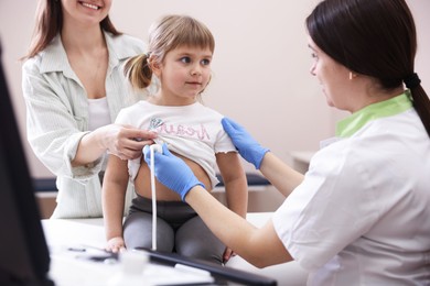 Photo of Sonographer conducting ultrasound examination of girl's heart. Mother and daughter having appointment with doctor in clinic