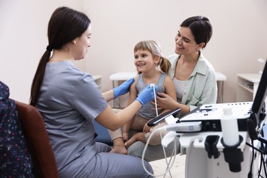 Photo of Sonographer conducting ultrasound examination of girl's heart. Mother and daughter having appointment with doctor in clinic