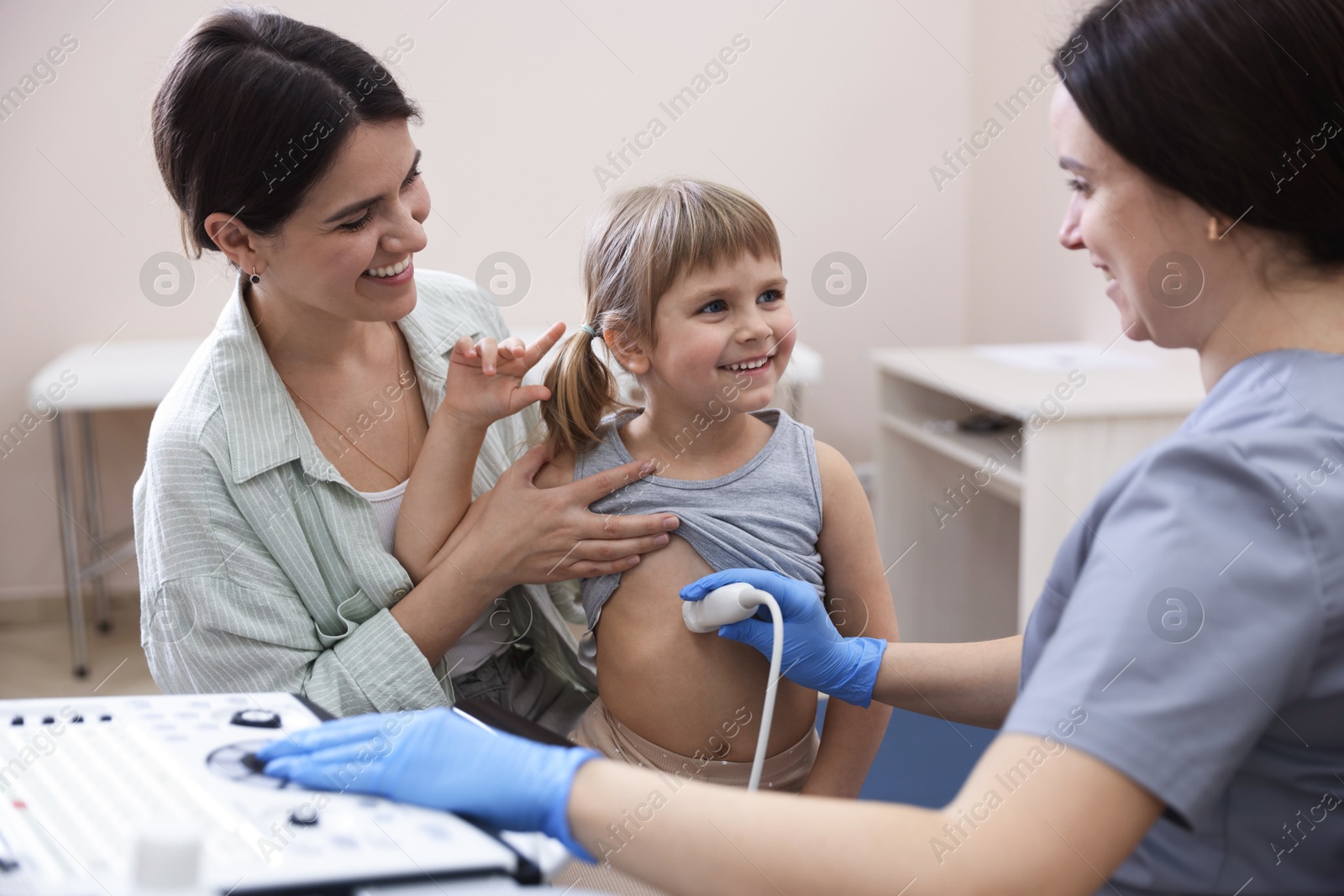 Sonographer conducting little girl's abdominal ultrasound examination. Mother and daughter having appointment with doctor in clinic Photo of Sonographer conducting little girl's abdominal ultrasound examination. Mother and daughter having appointment with doctor in clinic