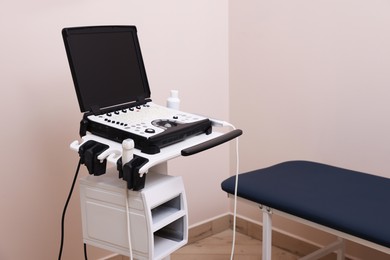 Photo of Modern ultrasound machine and examination bed in clinic