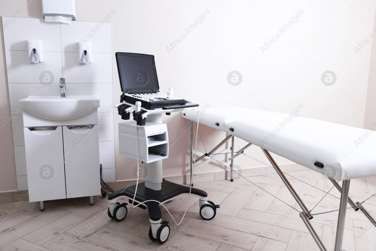 Modern ultrasound machine, sink and examination bed in clinic Photo of Modern ultrasound machine, sink and examination bed in clinic