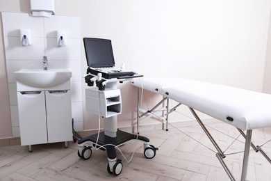 Photo of Modern ultrasound machine, sink and examination bed in clinic