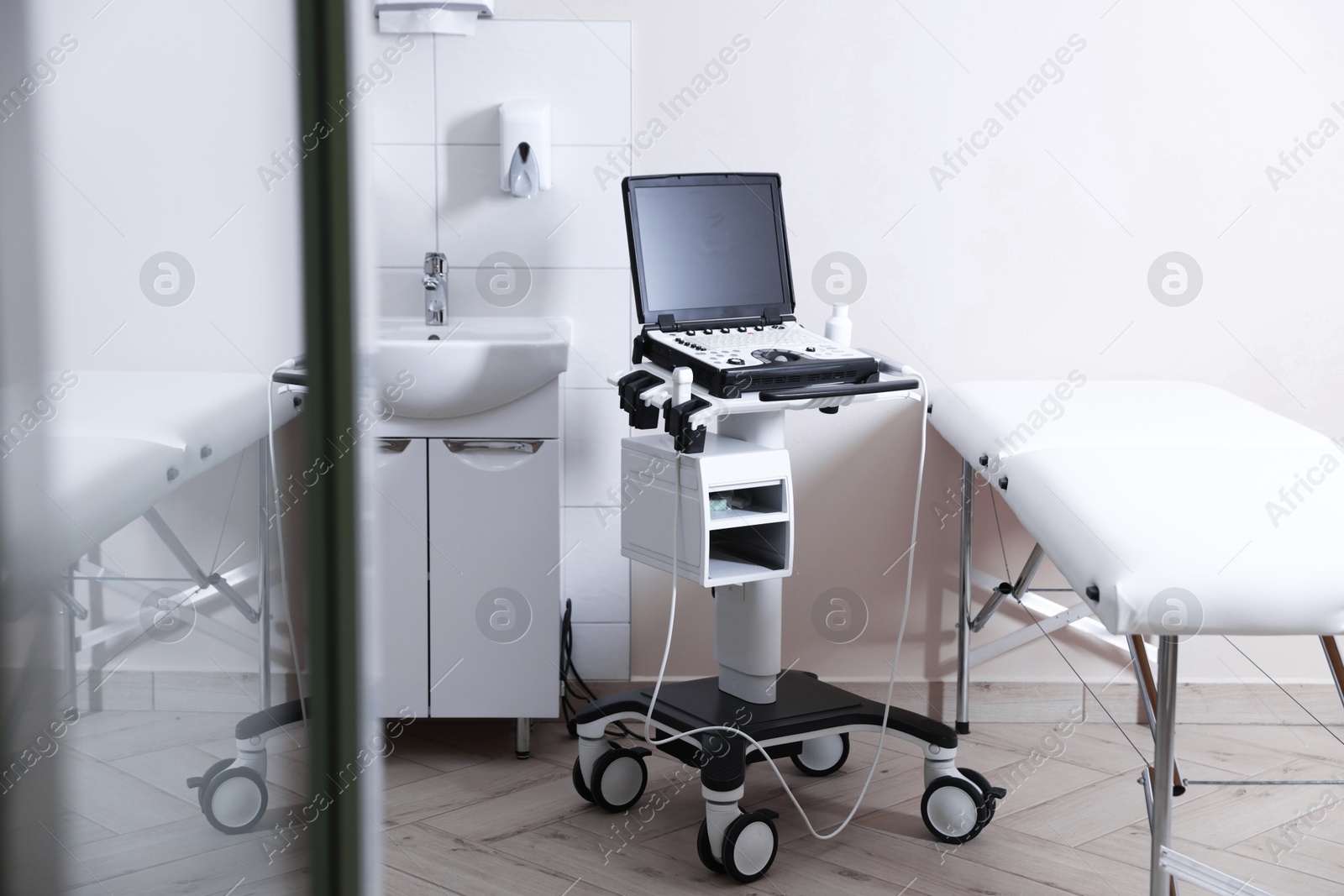 Modern ultrasound machine, sink and examination bed in clinic Photo of Modern ultrasound machine, sink and examination bed in clinic