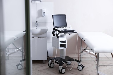 Photo of Modern ultrasound machine, sink and examination bed in clinic