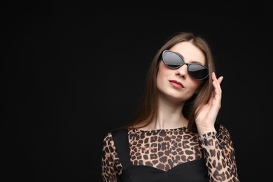 Photo of Fashionable portrait of beautiful woman in stylish outfit on black background. Space for text