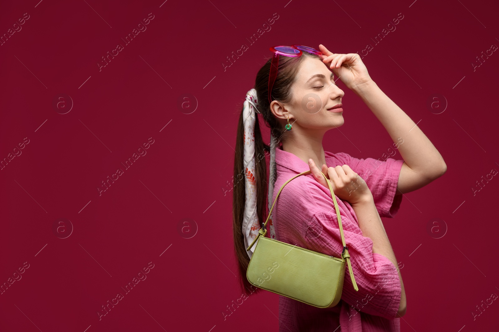 Fashionable portrait of beautiful woman in stylish outfit on dark red background. Space for text Photo of Fashionable portrait of beautiful woman in stylish outfit on dark red background. Space for text