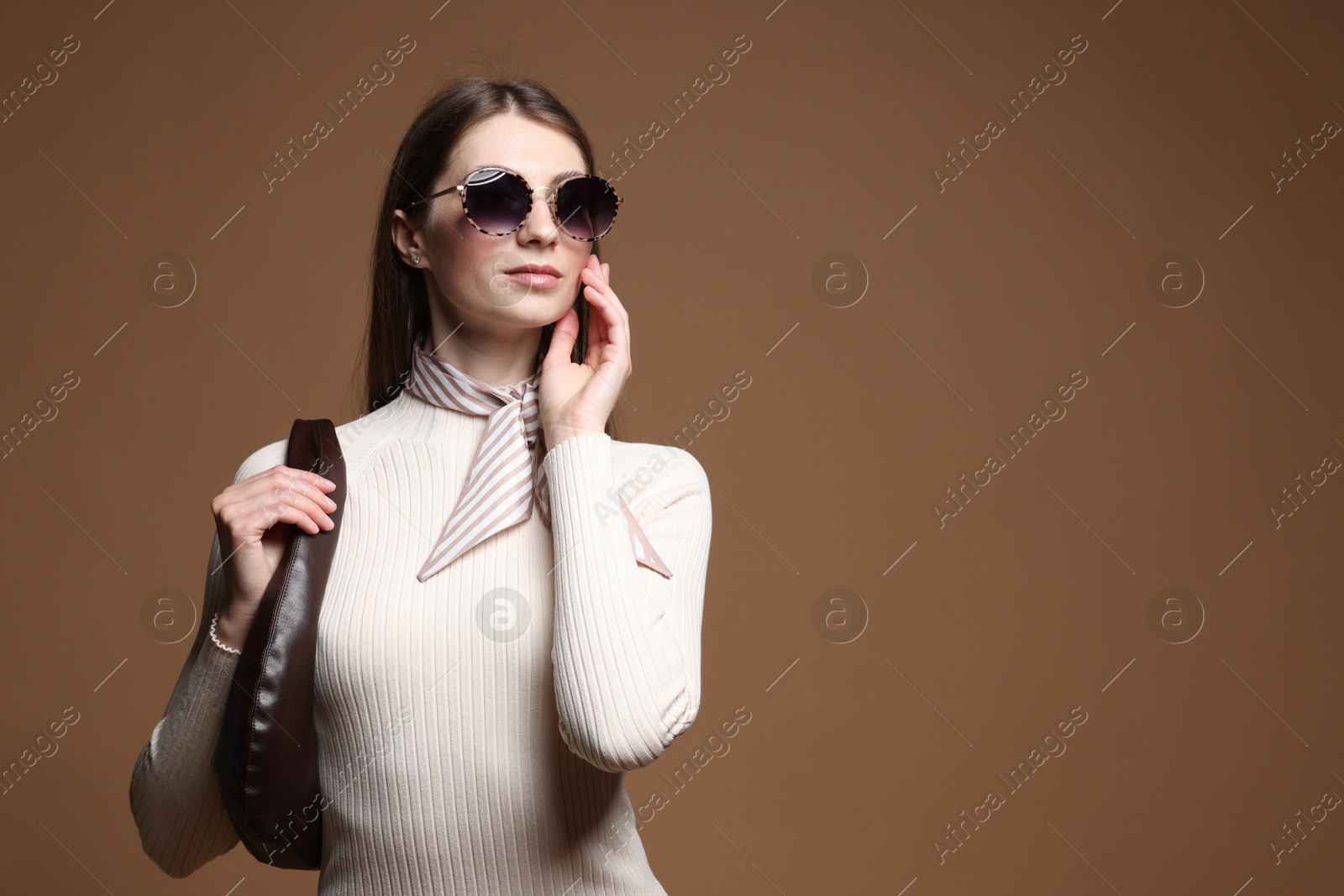 Fashionable portrait of beautiful woman in stylish outfit on brown background. Space for text Photo of Fashionable portrait of beautiful woman in stylish outfit on brown background. Space for text