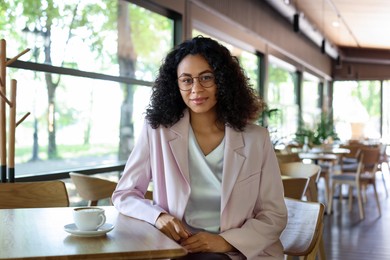 Photo of Portrait of beautiful Latin American woman at table in cafe