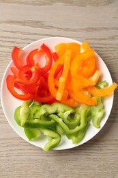 Photo of Slices of fresh colorful bell peppers on wooden table, top view