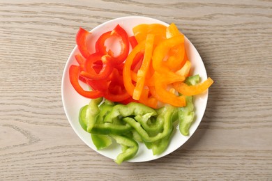 Photo of Slices of fresh colorful bell peppers on wooden table, top view
