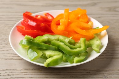 Photo of Slices of fresh colorful bell peppers on wooden table, closeup