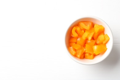 Photo of Pieces of fresh orange bell pepper in bowl on white wooden table, top view. Space for text