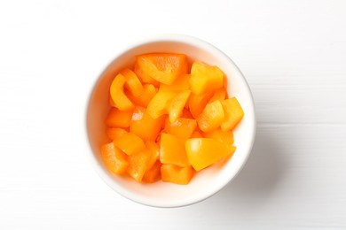 Photo of Pieces of fresh orange bell pepper in bowl on white wooden table, top view