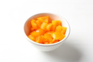 Photo of Pieces of fresh orange bell pepper in bowl on white wooden table, closeup