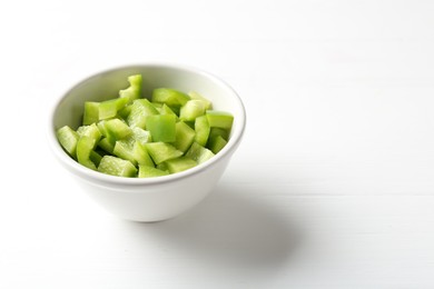 Photo of Pieces of fresh green bell pepper in bowl on white wooden table, closeup. Space for text