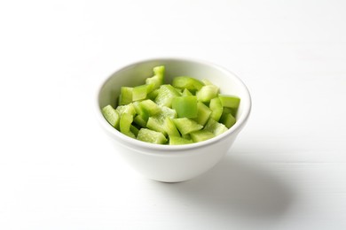 Photo of Pieces of fresh green bell pepper in bowl on white wooden table, closeup