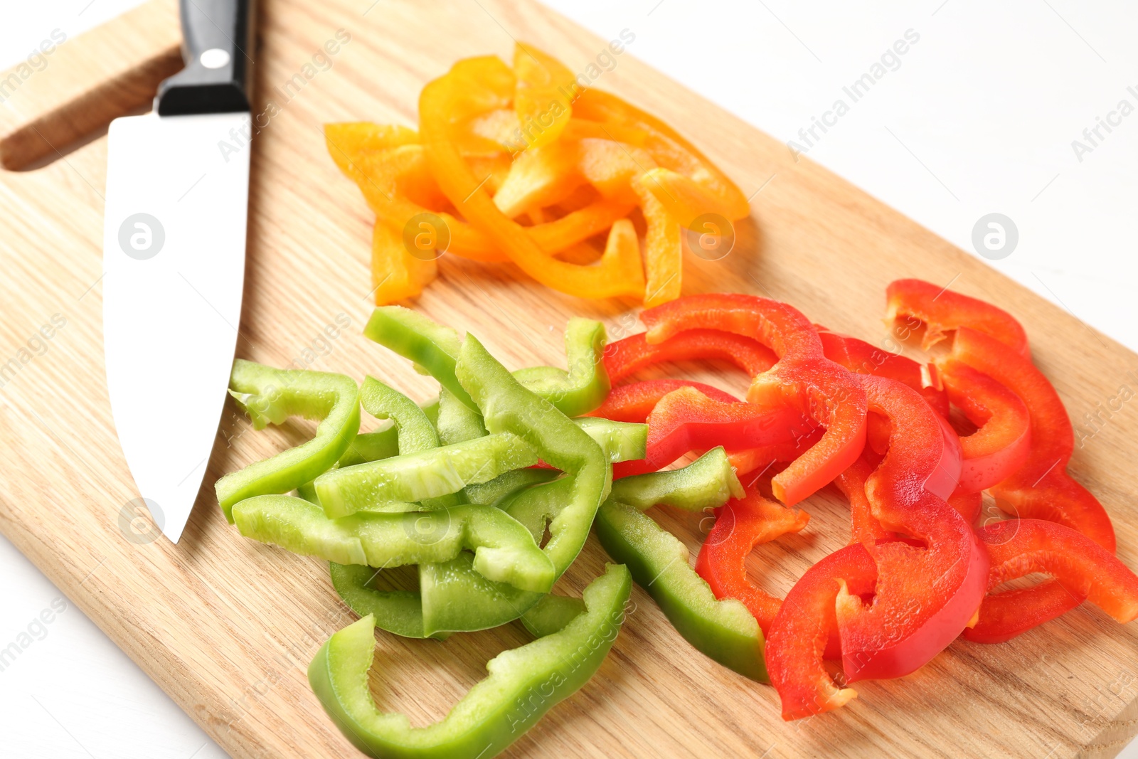 Slices of fresh colorful bell peppers and knife on white table, closeup Photo of Slices of fresh colorful bell peppers and knife on white table, closeup