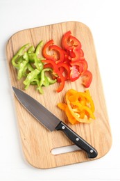 Photo of Slices of fresh colorful bell peppers and knife on white wooden table, top view