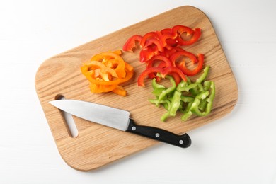 Photo of Slices of fresh colorful bell peppers and knife on white wooden table, top view