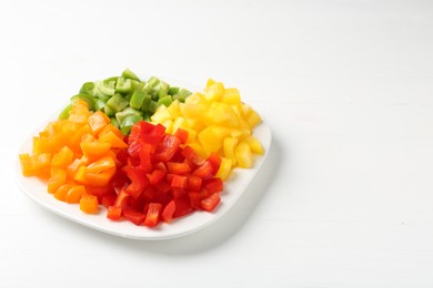 Photo of Pieces of fresh colorful bell peppers on white wooden table, closeup. Space for text
