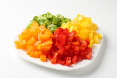 Photo of Pieces of fresh colorful bell peppers on white wooden table, closeup
