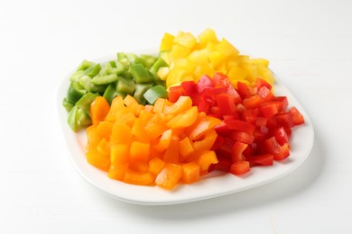 Photo of Pieces of fresh colorful bell peppers on white wooden table, closeup