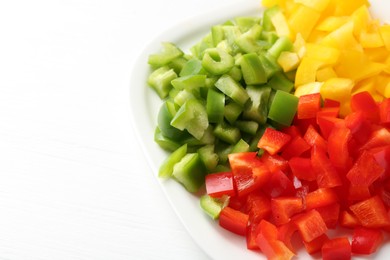 Photo of Pieces of fresh colorful bell peppers on white wooden table, closeup. Space for text