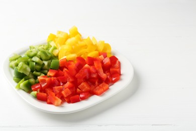 Photo of Pieces of fresh colorful bell peppers on white wooden table, closeup. Space for text