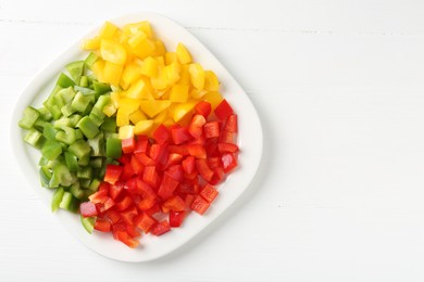 Photo of Pieces of fresh colorful bell peppers on white wooden table, top view. Space for text