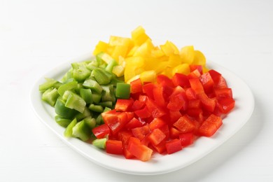 Photo of Pieces of fresh colorful bell peppers on white wooden table, closeup
