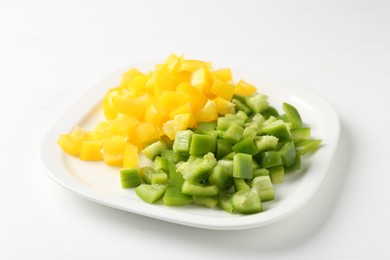 Photo of Pieces of fresh colorful bell peppers on white wooden table, closeup