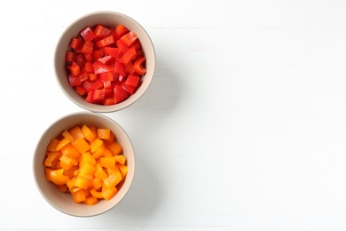 Photo of Pieces of fresh colorful bell peppers in bowls on white wooden table, flat lay. Space for text