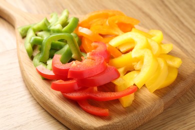 Photo of Slices of fresh colorful bell peppers on wooden table, closeup