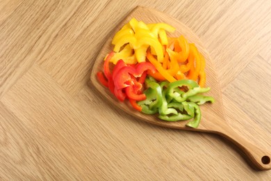Photo of Slices of fresh colorful bell peppers on wooden table, top view. Space for text