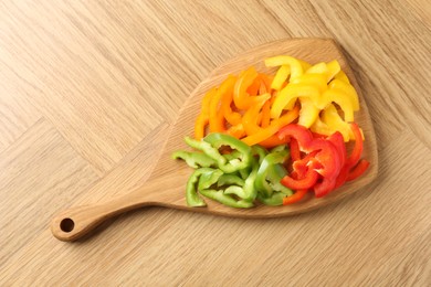 Photo of Slices of fresh colorful bell peppers on wooden table, top view