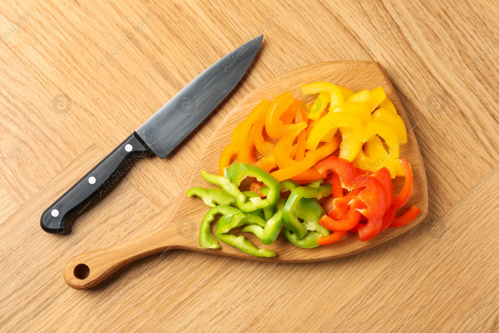 Slices of fresh colorful bell peppers and knife on wooden table, flat lay Photo of Slices of fresh colorful bell peppers and knife on wooden table, flat lay