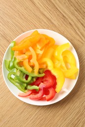 Photo of Slices of fresh colorful bell peppers on wooden table, top view