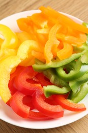 Photo of Slices of fresh colorful bell peppers on wooden table, closeup